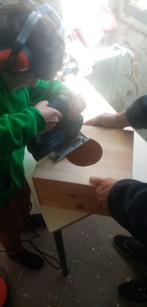 enfant utilisant une scie sauteuse dans le cadre d'un atelier des petits debrouillards
